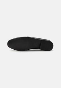 Semelle de chaussure noire avec une surface lisse, une légère courbe et un motif de grip texturé. Matériau en caoutchouc durable avec une forme arrondie.