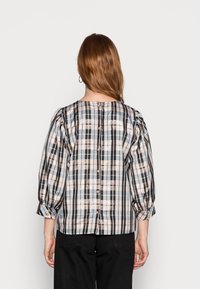 Ruokapaita vaaleissa pasteliväreissä, jossa on puffipäällysteet ja napitus takana. Se sisältää sinisen, beigen ja mustan kuvioiden sekoituksen.