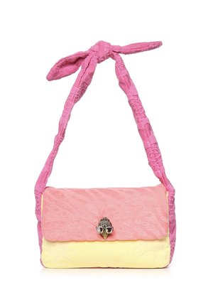 Bolso de hombro de tela suave en rosa y amarillo con una correa rosa retorcida y un emblema decorativo en tono plateado en el cierre de solapa.