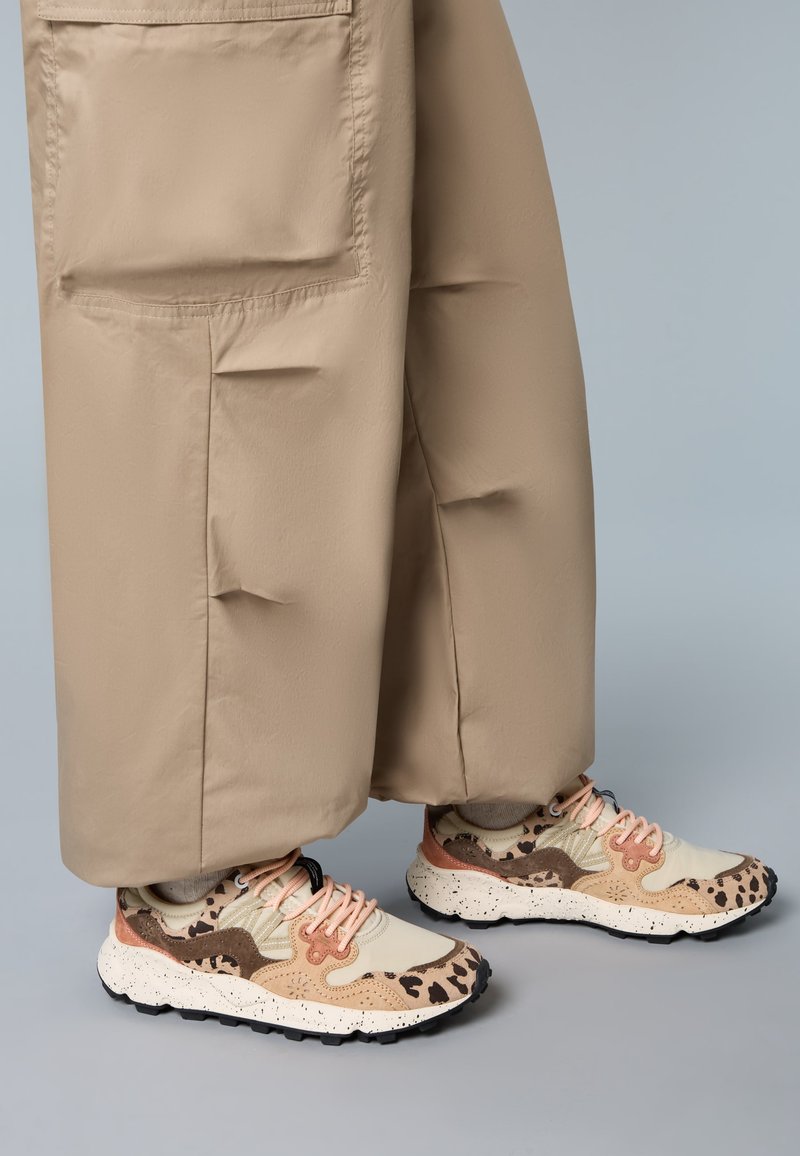 Sneakers with a beige and brown animal print, featuring mesh and leather panels, pink laces, and a textured white sole with black speckles.