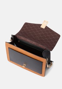 Brun och svart läderhandväska med guldfärgad hårdvara, med en framficka, ett öppet inre med ett zippered avdelning och ett mönstrat foder.