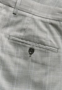Pantalones de cuadros grises con una textura sutil, que cuentan con un bolsillo trasero de ojal y un botón negro para el cierre, enfatizando el patrón de cuadros.