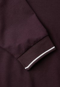 Donkerpaars sweatshirtstof met een gestructureerde mouwboord en een contrasterende witte streep. Zacht materiaal met een gladde afwerking.