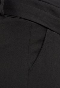 Black fabric with a smooth texture, featuring a wide waistband and a front pocket, exhibiting a simple, fitted design.