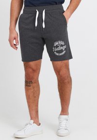 Charcoal gray shorts with white drawstring, featuring a front print and side pockets. Paired with white sneakers.