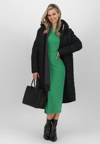 Cappotto imbottito nero, abito a coste verde, sciarpa grigia, borsa nera e stivali neri alla caviglia. Materiali lisci, design elegante,Silhouette aderente.