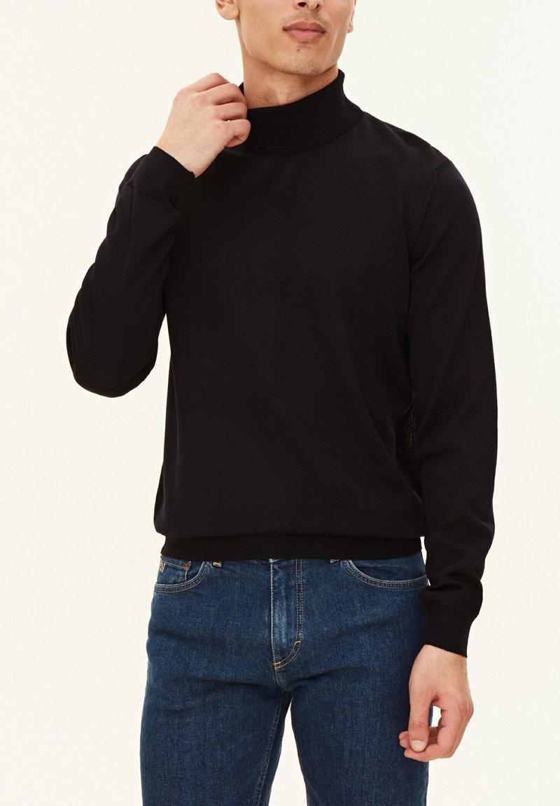 Schwarzer Rollkragenpullover aus glattem Stoff, mit langen Ärmeln und tailliertem Design, kombiniert mit blauen Jeans.