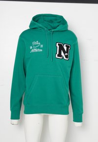 Grön huvtröja i mjukt tyg med en känguruficka, utrustad med broderad logotyp och text i vitt och svart på framsidan.