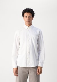Camicia bianca a bottone in cotone, con colletto, maniche lunghe, tasca sul petto e orlo curvo. Texture liscia con un design classico.