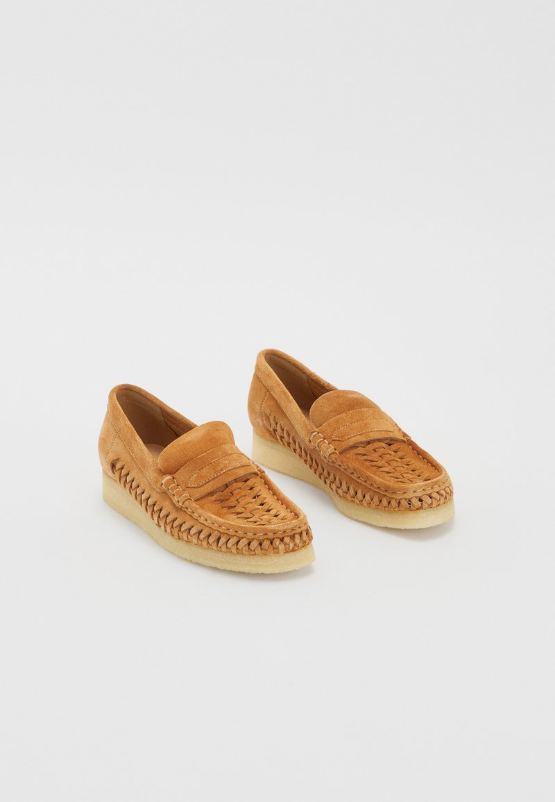 Brūni zamša loafers ar austiem detaļām un noapaļotu purngalu. Mīksts materiāls ar zemu papēdi un gumijas zoli ērtībai.