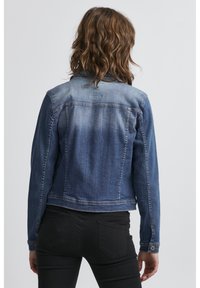 Giacca di jeans con una finitura blu sbiadita, chiusura con bottoni e due tasche per le mani. Presenta un colletto classico e una vestibilità tailored.