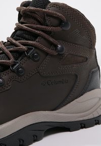 Hnědé voděodolné turistické boty Columbia s polstrovaným kotníkem, černými háčky na tkaničky a texturovanou béžovo-černou podešví.