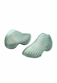 Dos objetos de vidrio verde translúcido que parecen olas fluidas, con texturas onduladas y superficies suaves; ambos tienen formas orgánicas.