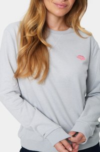 Felpa grigia con colletto a girocollo, polsini a costine e un accento di stampa di labbra rosa sul petto. Tessuto morbido, vestibilità rilassata, design minimale.