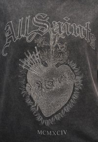 Μαύρο T-shirt με λεπτομερή σχεδιασμό καρδιάς με ασημένιες λεπτομέρειες, περιβαλλόμενο από στοιχεία όπως σπαθιά και ανθικά μοτίβα.