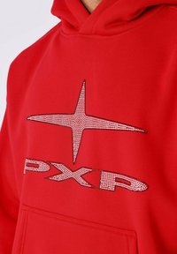 Sudadera roja de mezcla de algodón. Presenta un gráfico de estrella brillante hecho con strass y el texto "PXR" en el frente. Incluye un bolsillo frontal.
