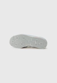 Adidas cipő talpnézete, amelyen textúrált szürke gumi talp látható körkörös mintákkal, világoskék díszítésekkel és márkajelzéssel a külső szélen.