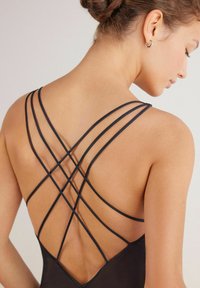 Zwarte bodysuit met een kriskras bandontwerp op de rug, benadrukt een gladde stof en een aansluitende pasvorm.
