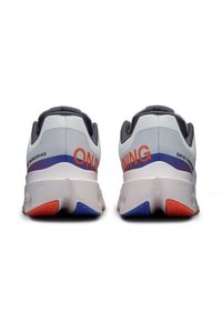 Baskets de course blanches avec des accents gris, présentant le texte « ON RUNNING » en orange. Semelle texturée avec des détails rouges et bleus pour une meilleure traction.