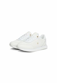 Zapatillas blancas con un exterior de cuero suave, diseño con cordones y sutiles acentos dorados. Presenta una suela texturizada y líneas limpias.
