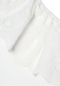 Weißes Stoffdetail mit floraler Stickerei, gewellten Kanten und einem strukturierten Hintergrund. Weiches, leichtes Material mit elastischem Rüschensaum.