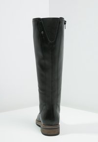 Bottes noires en cuir arrivant au genou avec une texture lisse, dotées d'une fermeture éclair à l'arrière et d'un talon empilé marron contrastant. Découpe en V en haut.