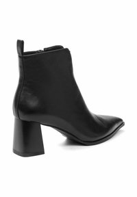 Bottine en cuir noir à bout pointu et talon bloc. Texture lisse avec un design épuré, dotée d'une tige haute et de coutures minimales.