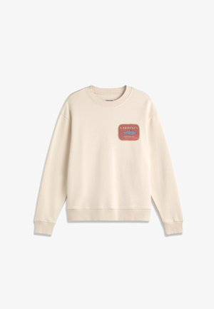 Sweatshirt beige à manches longues avec poignets et ourlet côtelés, présentant un petit graphique de boîte de sardines rouge et jaune sur le côté gauche de la poitrine.