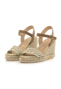 Braune Keilsandalen mit einer gewebten Jute-Plattform, die metallische Akzente und einen Schnallenverschluss aufweist. Strukturiertes Fußbett mit einem gemusterten Design.