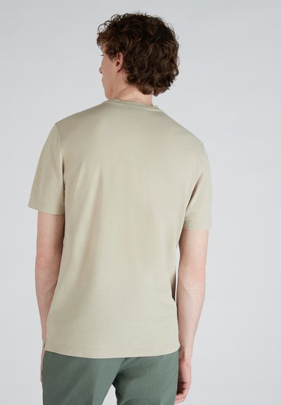 Maglietta a manica corta beige chiaro con scollatura rotonda, realizzata in tessuto morbido. La parte posteriore presenta un design semplice senza motivi o accenti.