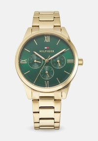 Orologio da polso in oro con quadrante rotondo verde, numeri romani, tre sottoquadranti e bracciale in metallo a maglie. Presenta il logo del marchio sopra il 6.