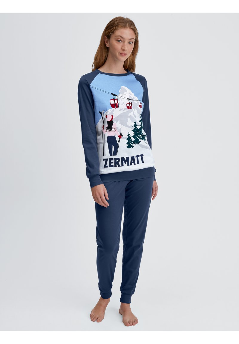 Lange mouwen pyjama set met een grafisch ontwerp van bergen en een skier. Blauwe bovenkant met donkerblauwe mouwen, marineblauwe broek en ribgebreide manchetten.