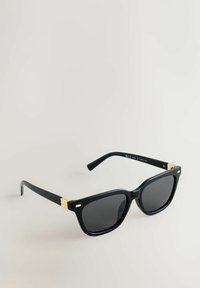 Sorte solbriller med firkantet stel, mørke linser og gyldne detaljer på stængerne. Fremstillet af plastik med en glat overflade.