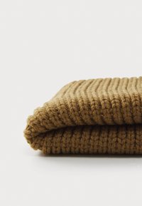 Coperta lavorata a maglia in marrone caramello, piegata per mostrare il motivo a costine e il filato spesso, con un aspetto morbido e intrecciato.