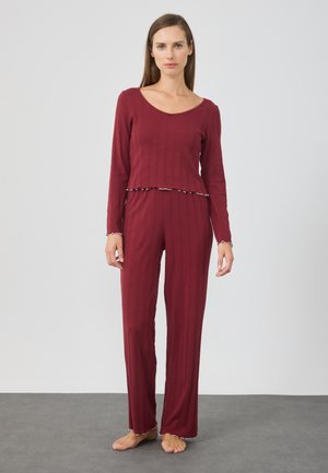 Burgundy pyjamaset med långa ärmar och utsvängda byxor, med en kort topp som har volangnederdel och ribbad textur. Mjuk tyg.