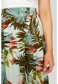 Jupe florale avec une base bleu clair ornée de motifs de feuilles verts, bruns et roses. Taille élastique et tissu doux et fluide.