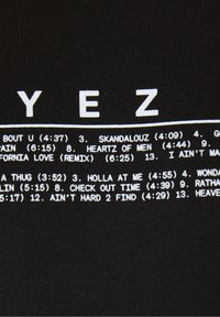Černá látka s bílým tištěným textem s názvy písní a jejich délkami. Čisté uspořádání písma, které výstižně zobrazuje informace o skladbách.