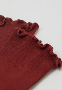 Burgundy ribbade strumpor med en volangkant. Mjuk textur med en jämn färg och lätt stretch, lämpliga för avslappnad användning.