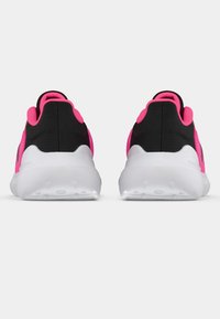 Zwarte sportschoenen met roze accenten. Gevoerde zool en gestructureerde stof. Gladde witte zool met gripstructuren. Achteraanzicht.