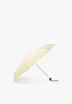 Złożony jasnobeżowy parasol z metalowym trzonkiem i czarną rączką, leżący otwarty pod kątem na białej powierzchni.