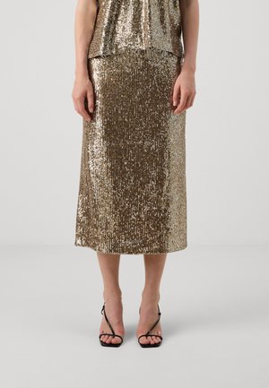 Gouden paillettenrok met een rechte silhouet, knielang, gecombineerd met zwarte sandalen met bandjes, met een gladde, reflecterende textuur.