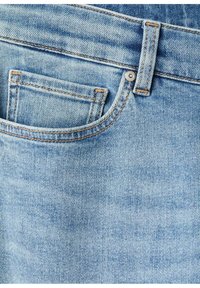 Vaaleansiniset farkut, joissa on etutasku, näkyvät saumat ja metallinen nappikoriste vyötärön lähellä. Sileä pinta.