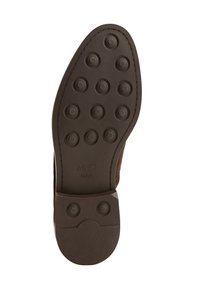 Semelle de chaussure en caoutchouc brun avec des motifs de grip circulaires, bords lisses et talon texturé. Présente le marquage de la marque "MNG MAN" sur la surface.