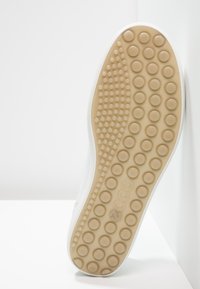 Hvit sneaker med glatt overdel, gummisåle med sirkulært grep mønster og lette beige detaljer. Minimalistisk design uten synlige logoer.