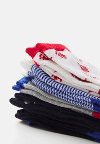 Ein Stapel von Socken in verschiedenen Farben: rot und weiß mit Muster, blau gestreift, grau und schwarz. Strukturierter Stoff, einfarbige und gemusterte Designs.