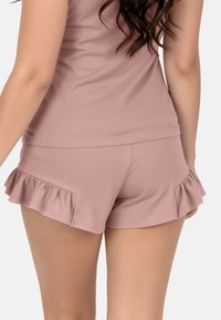 Pantalones cortos de algodón rosa con detalles de volante en el dobladillo. Textura suave y diseño ajustado con bolsillos laterales. Adecuados para uso casual o para dormir.