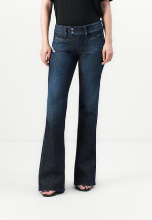 Jean évasé bleu foncé en denim, présentant des poches avant, une fermeture à deux boutons et un ourlet effiloché subtil en bas.