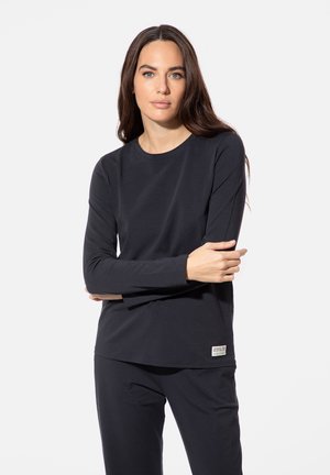 Black long-sleeve shirt made of soft fabric, featuring a round neckline and a small label at the hem. Styled with matching pants.