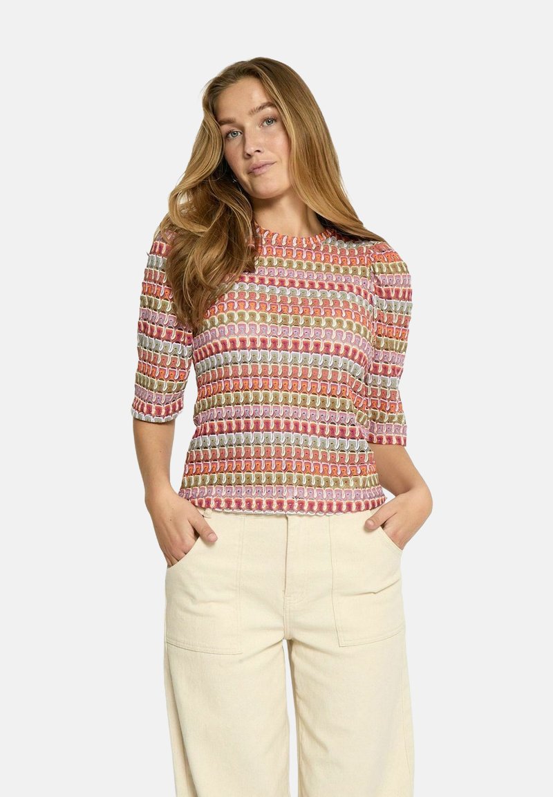 Haut multicolore à manches courtes avec un motif géométrique répétitif en rose, beige, rouge et blanc, fabriqué en tissu léger.