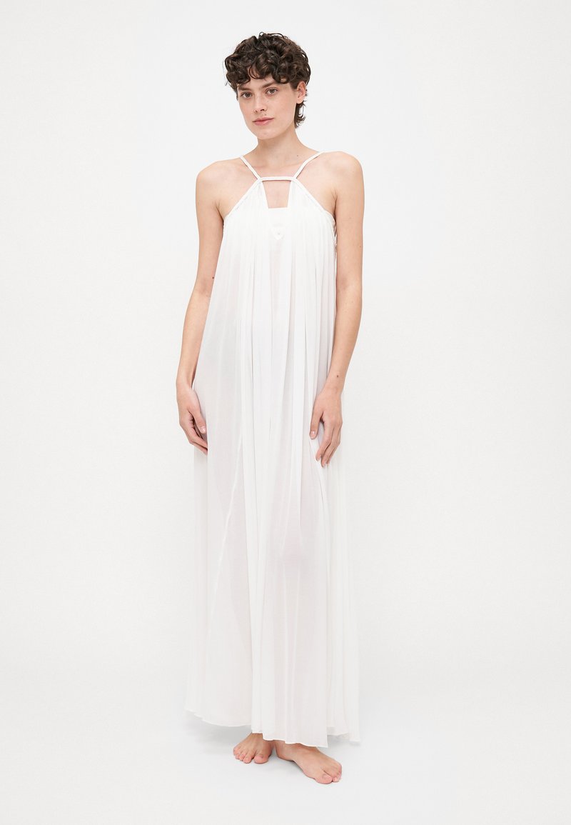 Robe maxi blanche en tissu transparent, avec un col halter, des fines bretelles et une conception fluide et superposée avec une ouverture en forme de clé au niveau de la poitrine.